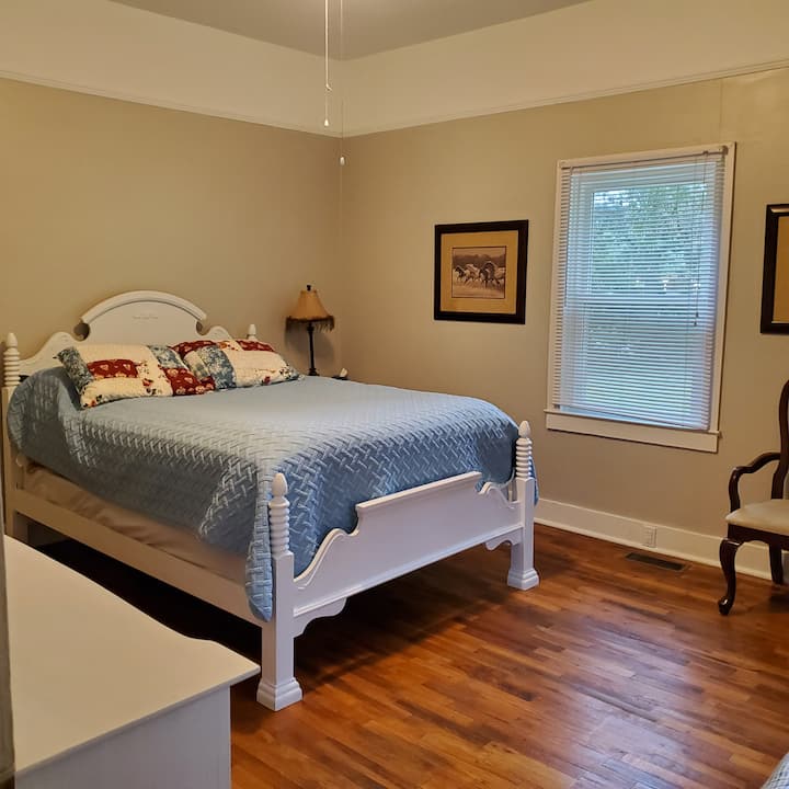 Dormitorio principal con cama tamaño queen, mesita de noche, vestidor completo y armario con perchas.