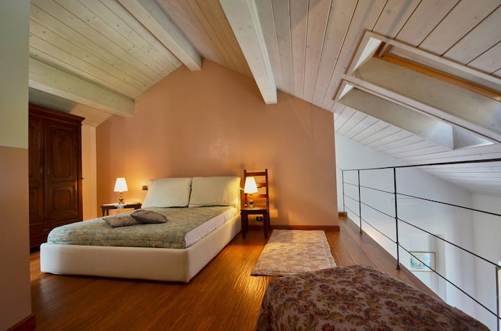 Appartamento "Matisse", vano notte, letto matrimoniale, guardaroba e seduta con tappeto. Ampio spazio vivibile.