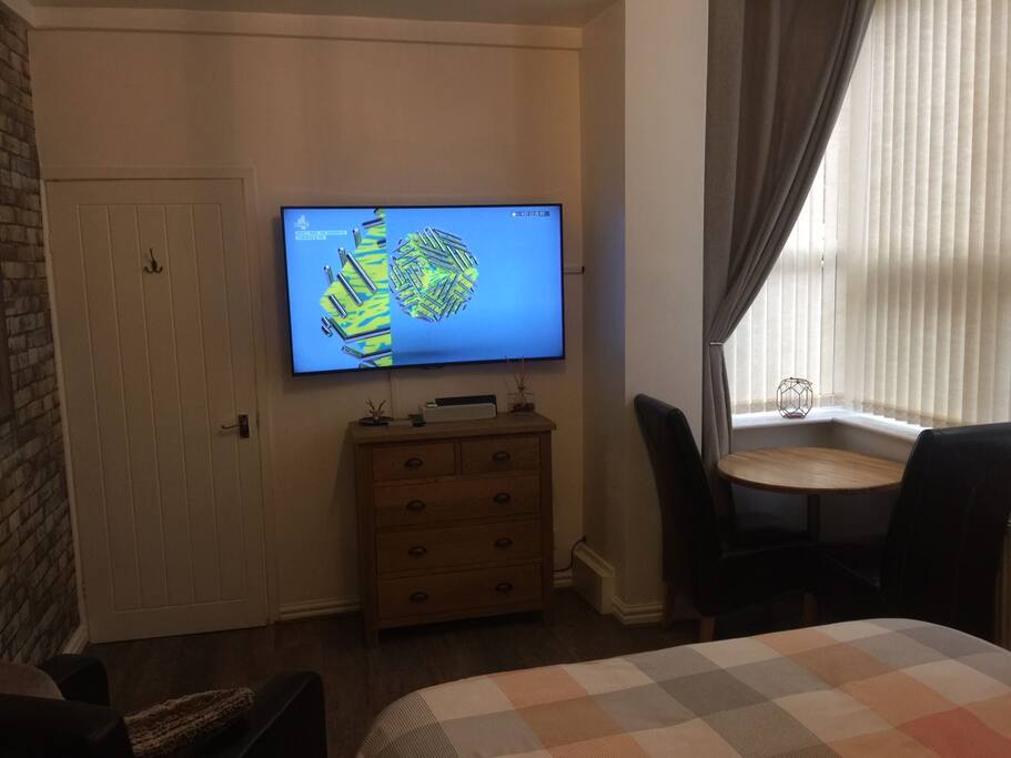 Lounge area of bedroom with Panasonic 55 inch curved 4k SMART TV and docking station