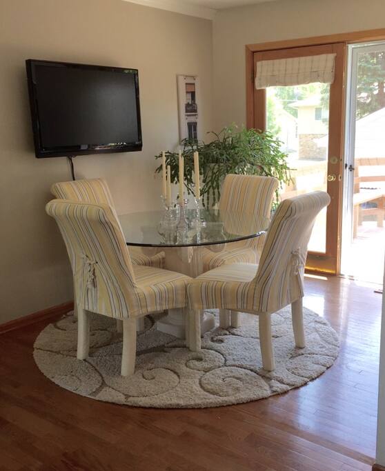Dining area off kitchen that walks out to multi-level deck, patio and yard with fence. Flat screen TV above table with satellite television.