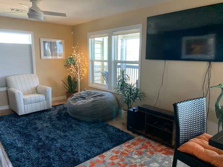 منطقة معيشة مع كرسي وحقيبة فاصولياء وأريكة مستلقية.  تلفزيون/مشغل بلوراي/دي في دي.  إطلالات رائعة على النهر من النوافذ!