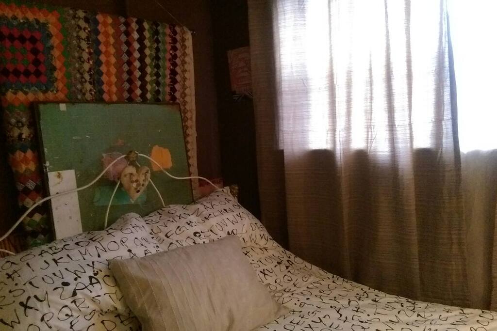 Antique Wrought Iron Bed in Cozy Art Filled Space with morning light. Couples please note one side of the bed is against the wall:)