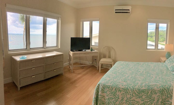 חדר שינה ראשי עם נוף לים ממיטת קווין סייז.