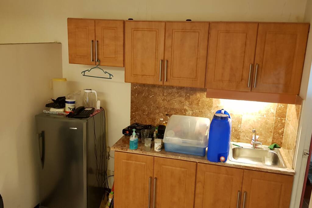 Fridge, landline, and cooking area. Frying pans will be inside the cabinet. Plates and glasses can be used.
