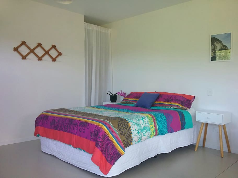Queen bed with wardrobe space behind the curtain.