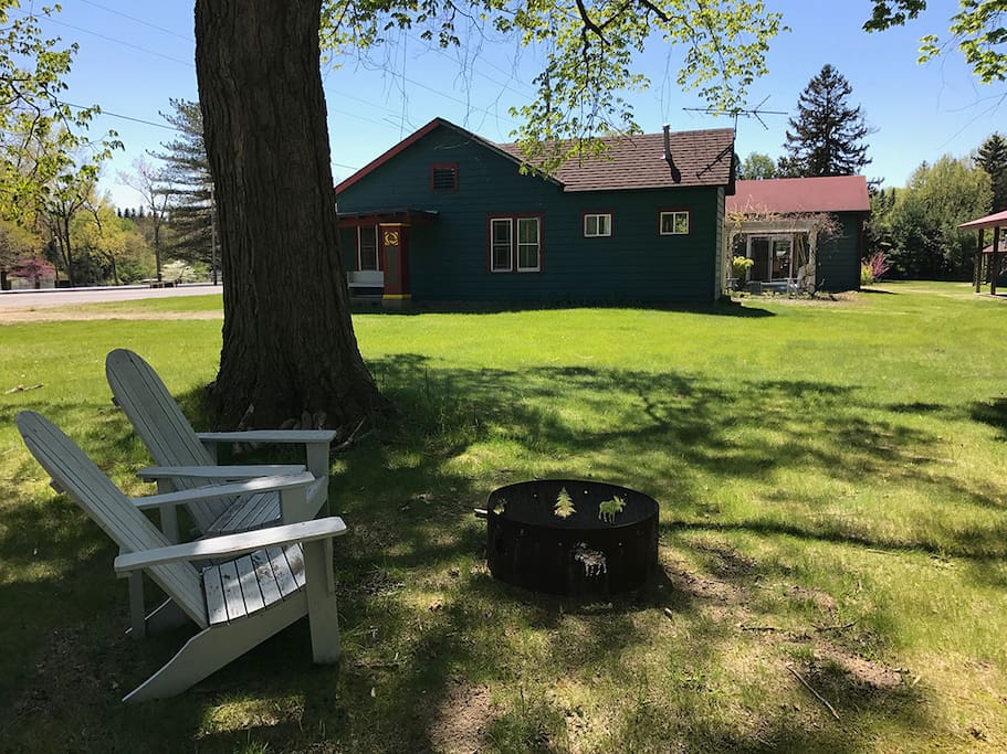 Large side yard with inviting fire ring and comfortable adirondacks is made for relaxing