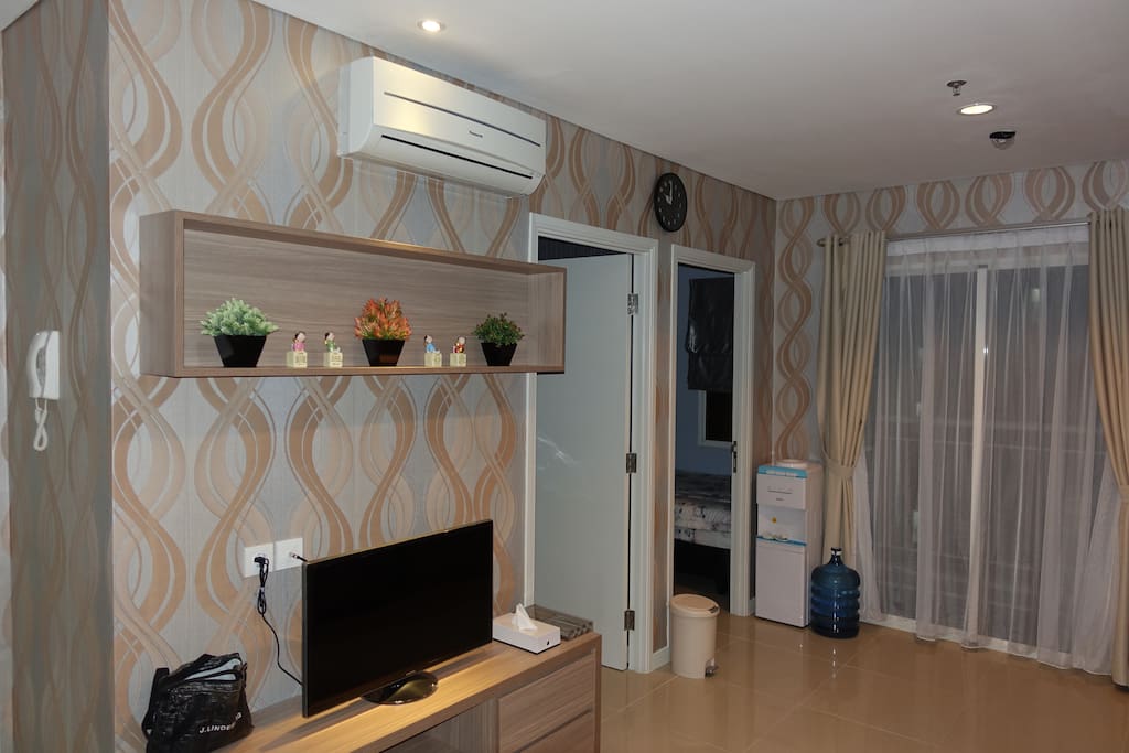 Living Area equipped with comfortable sofa, TV, Air Conditioning and Coffee Table.