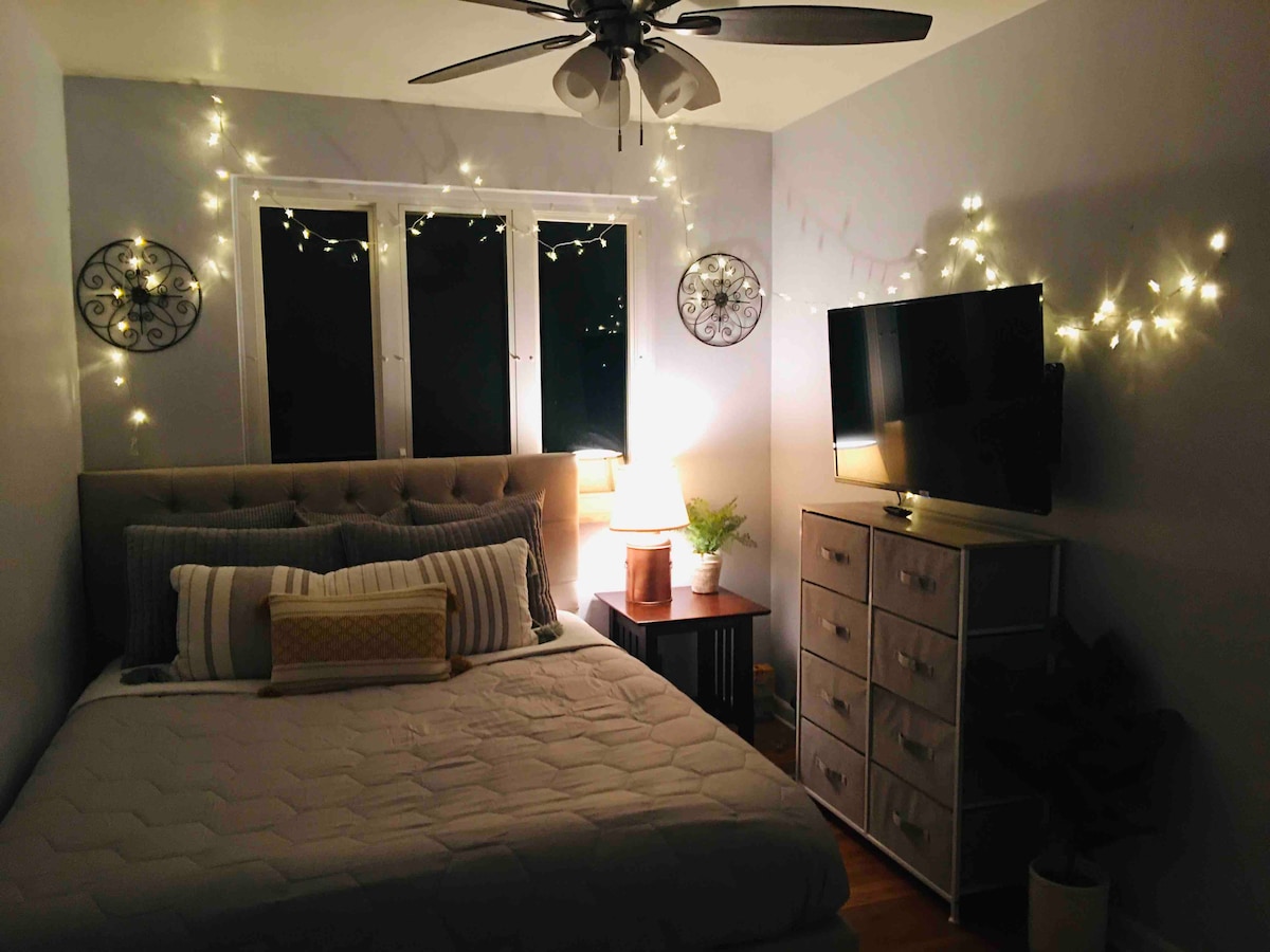 غرفة نوم مريحة بسرير كوين مريح وأسرّة عالية الجودة ومروحة سقف وتلفزيون ذكي UHD خاص بها