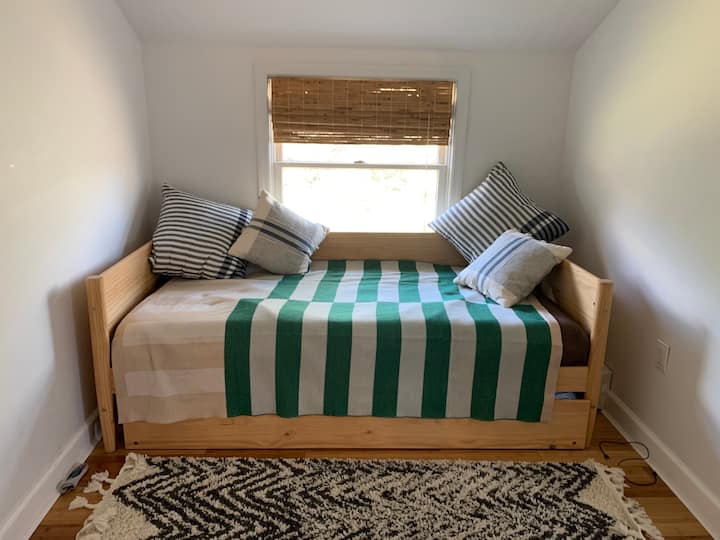 Upstairs bedroom. Twin trundle bed. Reading chair and desk. Window AC unit in the summer