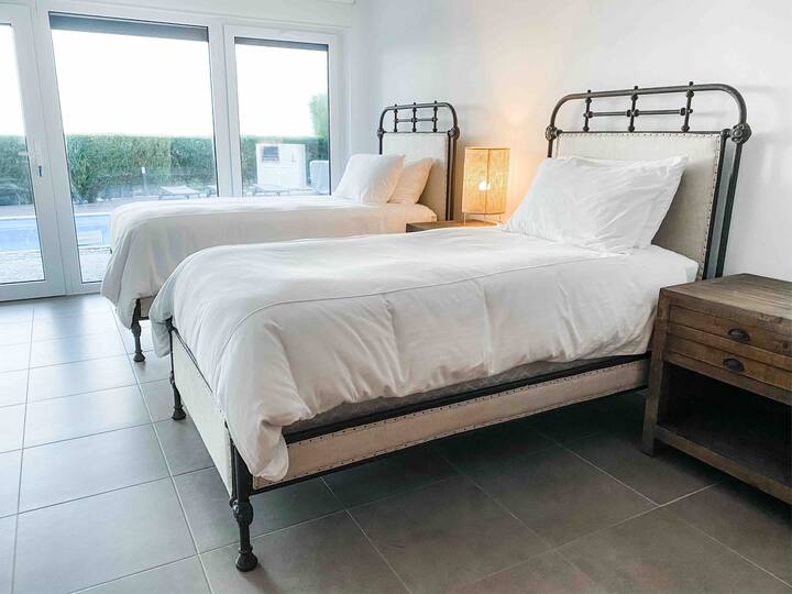 5th en-suite bedroom with two single French Académie beds, TV, and access to pool.