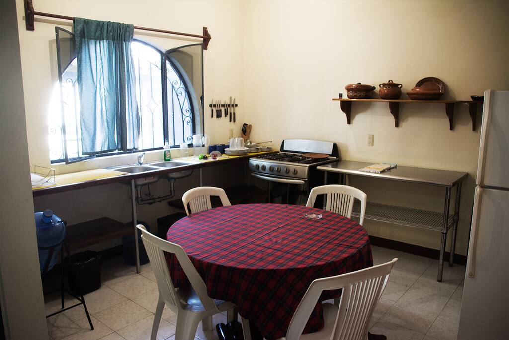 Cocina equipada con estufa con horno, refrigerador, vajilla, así como utensilios de cocina y ventilador.