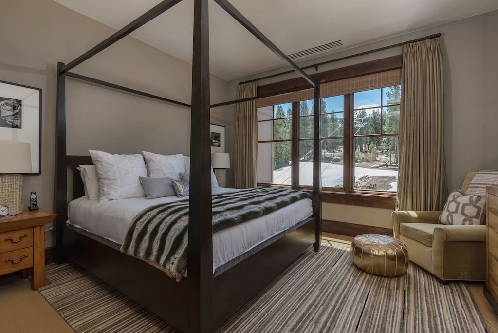 A regal king-size bed in a master bedroom with views looking directly over the ski run and gondola