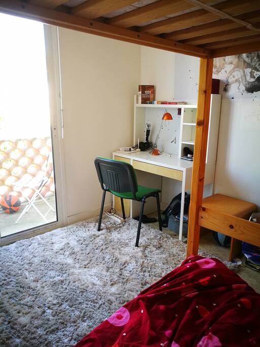 Chambre avec balcon, vue agréable sur jardin boisé.