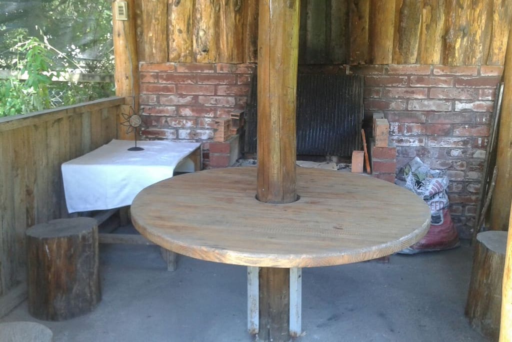 quincho con parrilla y asador mesa anexa y mesa redonda en el centro con pisos de troncos posee luz y enchufe