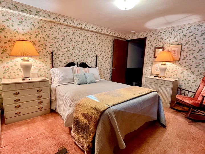 El segundo dormitorio en el nivel inferior tiene una cama tamaño queen con cabeza ajustable.  También hay un armario grande, un armario grande y un par de cómodas para tu uso.  Y una mecedora termina el espacio acogedor.