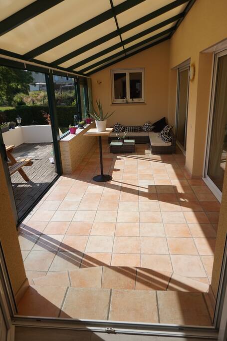 Véranda qui s'ouvre presque totalement sur la terrasse en bois