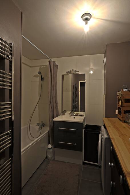Vue salle de bain avec baignoire et lave linge/seche linge