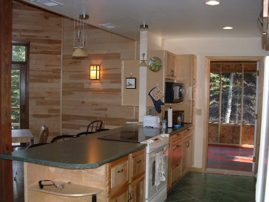 Kitchen is open to dining and living room. Screened-in back porch visible beyond.