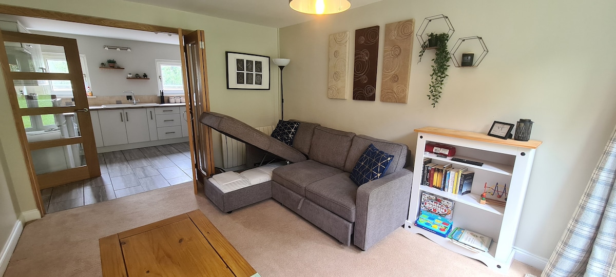 Woonkamer met slaapdiva. Beddengoed opgeslagen in poef.