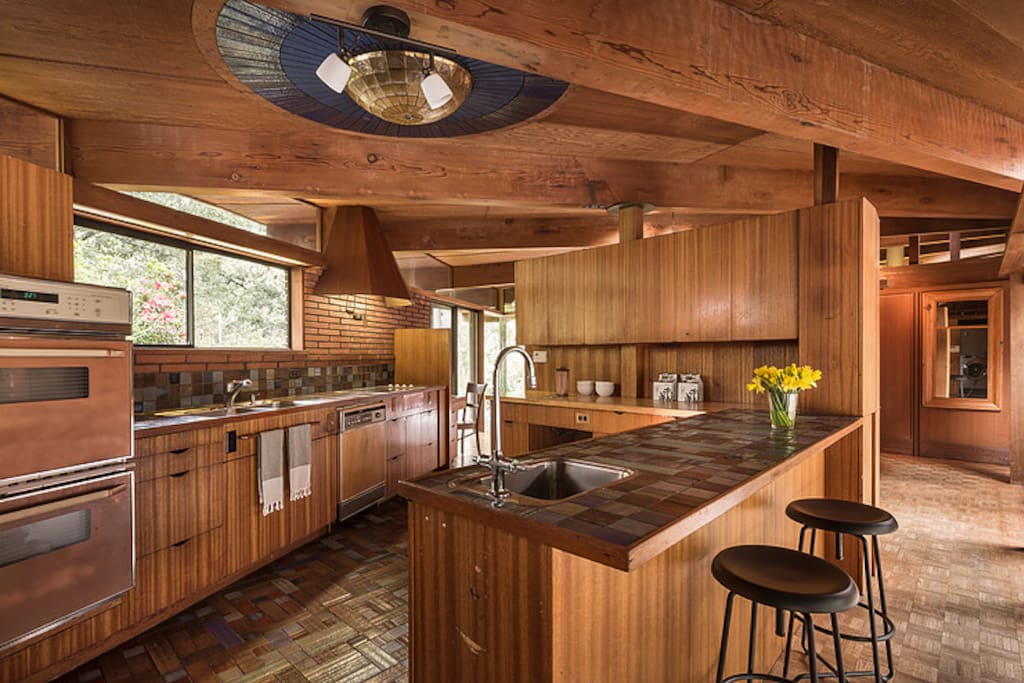 In the kitchen, the mother of pearl light fixture is surrounded by three concentric rings of dark blue tiles from Sausalito-based Heath Ceramics. Architect Dan Liebermann actually installed the now famous Heath tiles in the kitchen, baths, pool, and fountain.