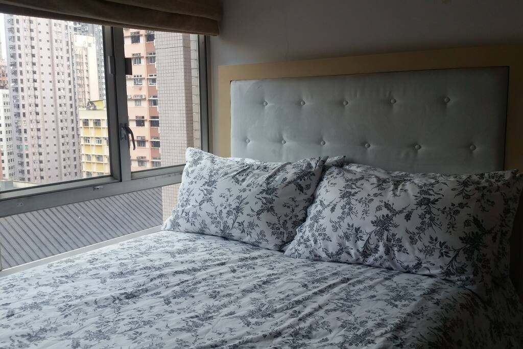 Queen size bed with a duvet and four pillows in a bright room (curtains available). Storage available for your luggage, wardrobe with hanging rail, silent aircon.