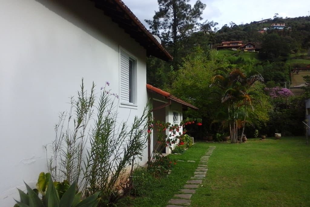 Vista lateral da casa. Jardim e estacionamento.