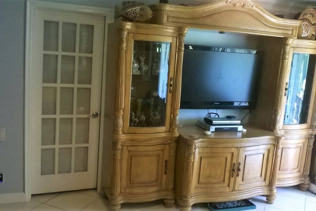 Living area entertainment hutch with large plasma TV and surround sound system.