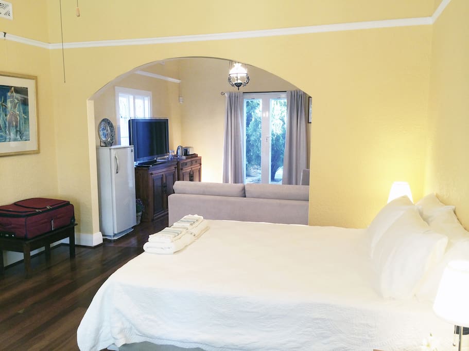 Queeen size bed in large room with adjoining TV and sitting room