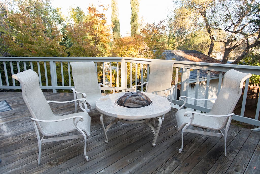 Private backyard deck with lounge chairs, fire pit, and barbecue.