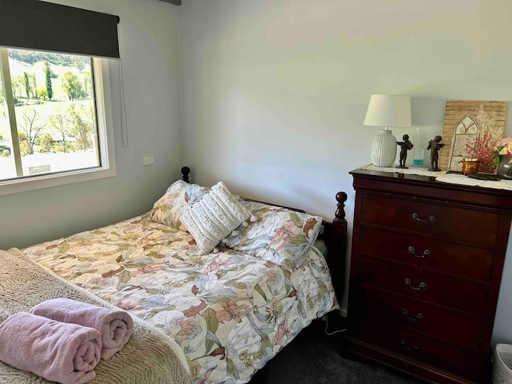 Sutto 's Hutut Second Bedroom, con una cómoda cama tamaño queen y una hermosa decoración de arbustos.