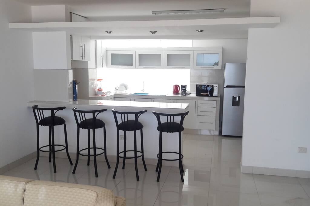 Comodas sillas y moderna barra que conecta kitchenet con la sala