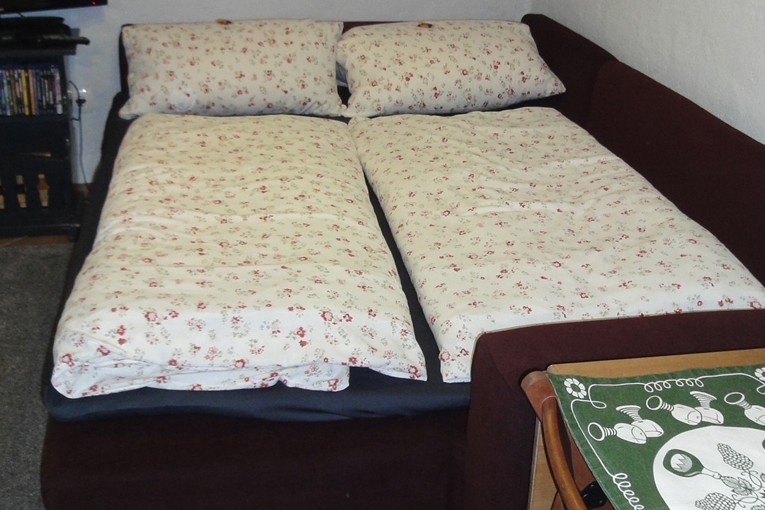 Rozkladacia pohovka v obývacej izbe s priestrannou posteľou.
