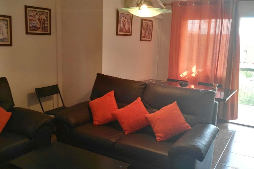 Sofá, mesa, aire acondicionado y salida a terraza del salón-comedor.