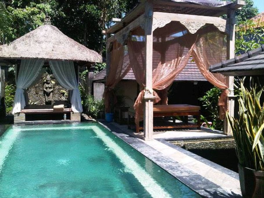 Pool with massage area, gazebo in the back and water feature in the back
