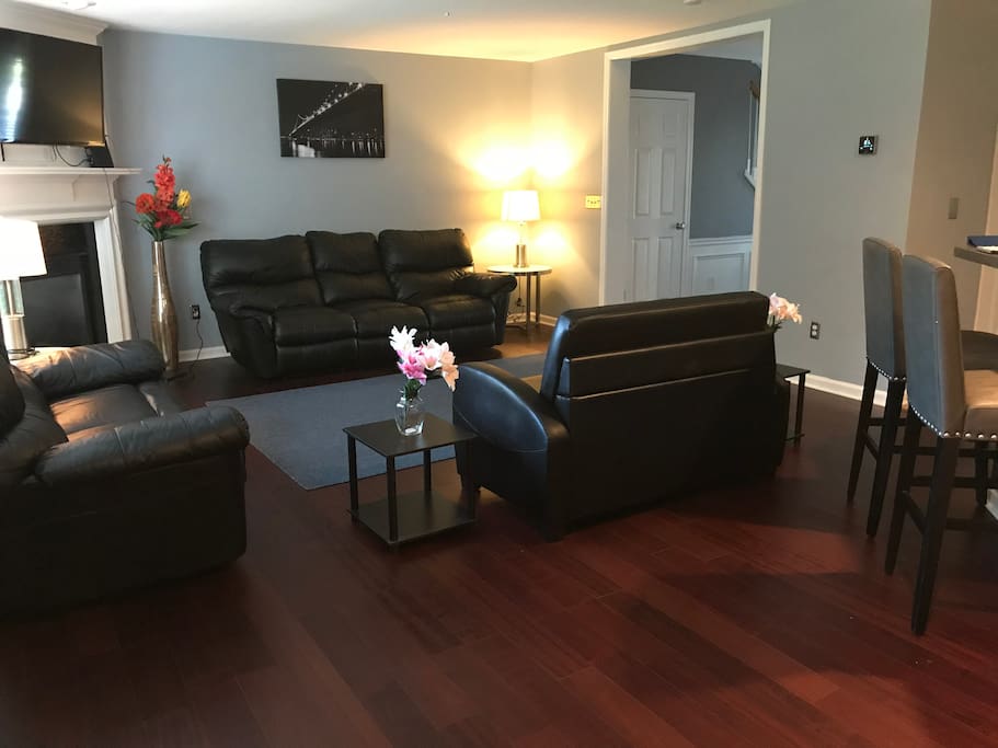 Living room hardwood floors & black leather furniture with twin pull out bed.