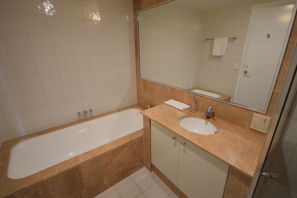 The bathroom has a full size bath and shower and marble finishes