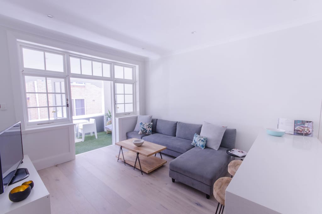 Lounge opening out to large balcony with faux grass, dining suite & wicker lounge.