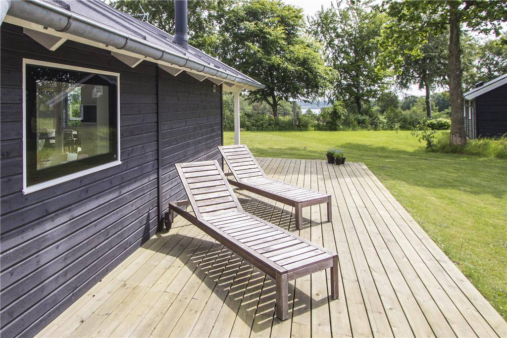 Hus mod syd med kig til fjorden mellem træerne
