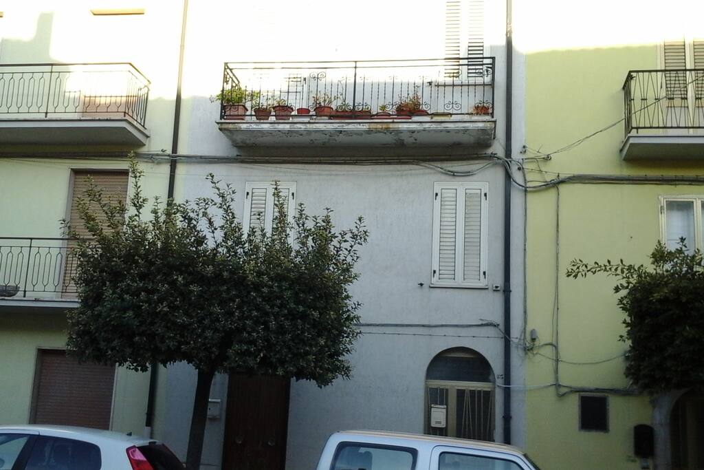 l'entrata della casa la porta a destra , il parcheggio davanti, e la facciata bella luminosa con il balcone che guarda la Maiella la montagna.
