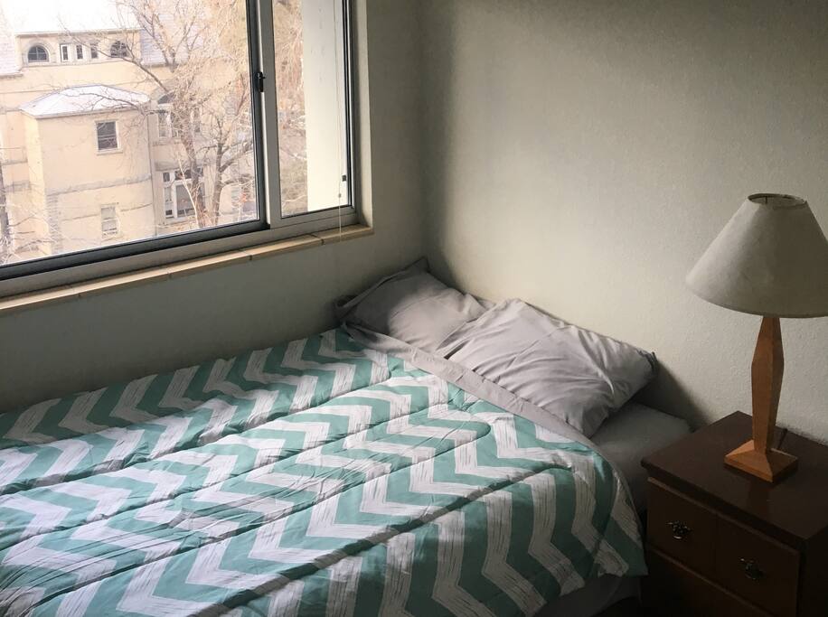Sunny room with a bed right next to the window.