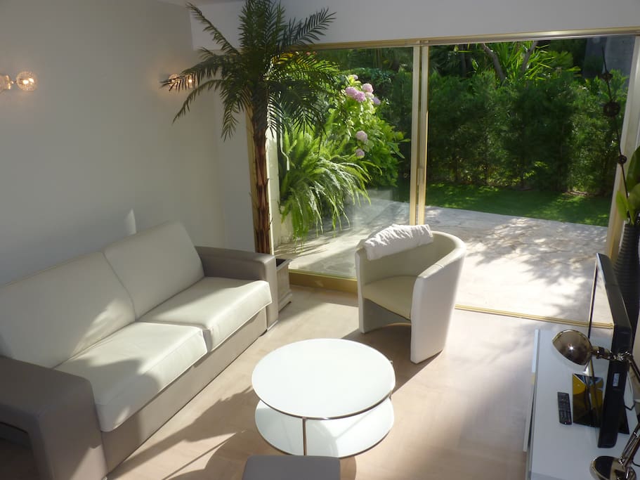 Salon ouvert sur la terrasse et le jardinet privé avec lits de soleil, sans vis-à-vis