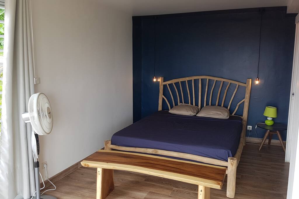 un jolie coin chambre avec lit en branche de teck et banc en bois massif