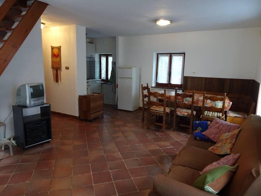 Salone con angolo cottura, tavolo e divano letto