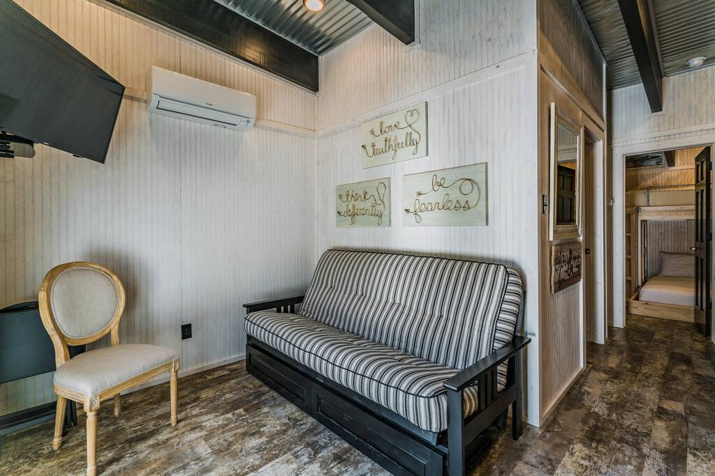 Living area with flat screen cable TV, AC/Heat unit, ceiling fan, couch folds out into a full