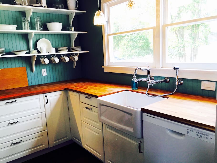 Farmhouse sink with wall mounted faucet and sprayer. Large kitchen window lets in lots of natural light.