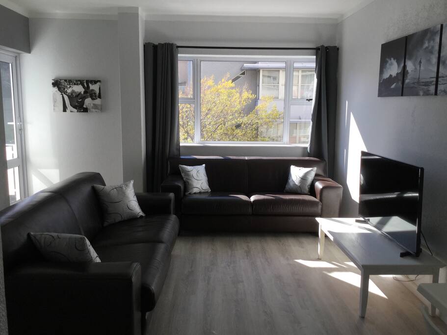 Leather couches in the living area and a 48 inch smart TV. (Balcony door on the far left)