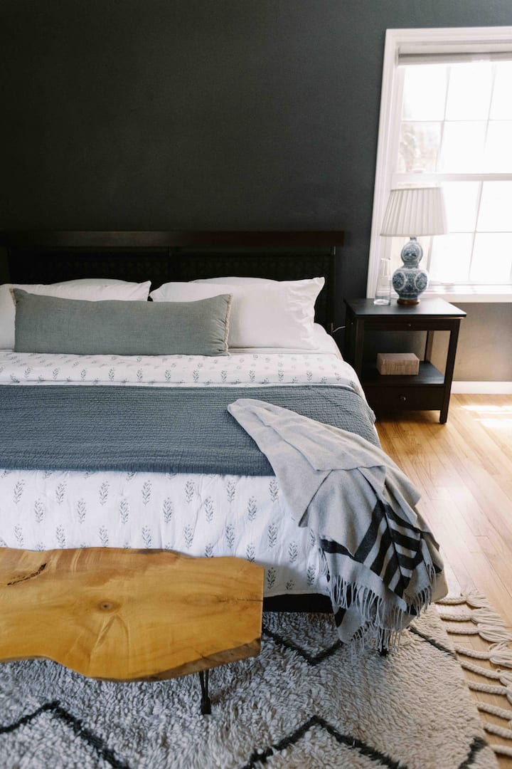 Moody meets spacious bedroom with king-size bed, Tuft & Needle mattress and ceiling fan.