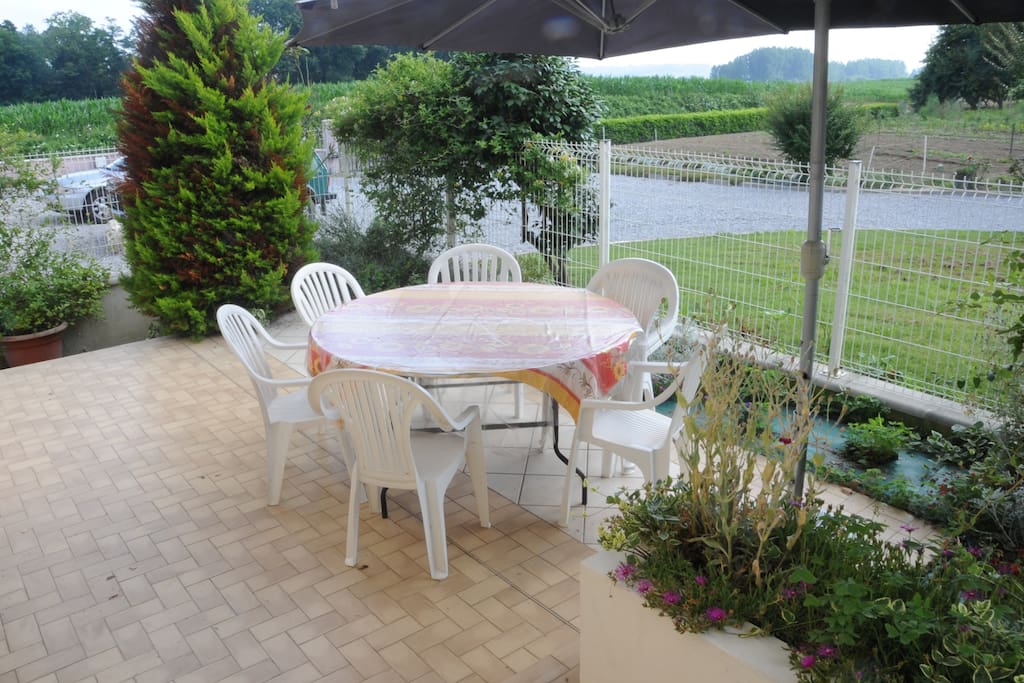 Terrasse privative, avec table ronde de 8 à 10 personnes, fauteuils, parasol et barbecue.