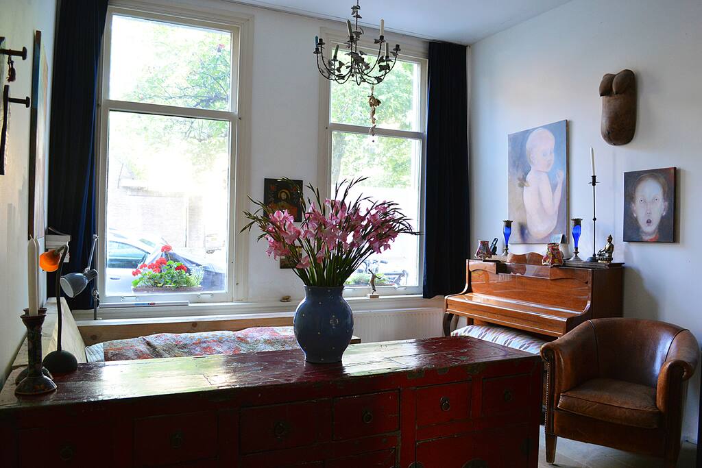 Overview of the rear of the living room. This part includes a double bed and a piano.