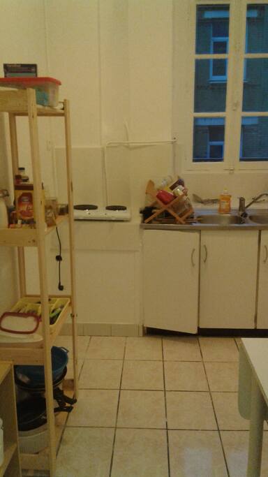 La cuisine: de la vaisselle, une table et des chaises, un four et une plaque de cuisson